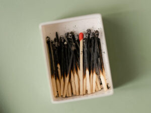 Symbolbild für Erschöpfung: abgebrannte Streichhölzer in einer Schachtel – nur eines ist noch unversehrt